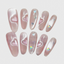 Long almond press-on nails with pink cat eye shimmer, heart accents, and holographic star charms.