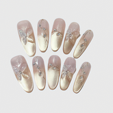 Almond-shaped press-on nails with gold gradient finish, 3D butterfly decorations, and crystal vines.