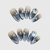Almond-shaped black and brown gradient press-on nails with 3D rhinestones and a large crystal gem, featuring a bold and elegant ombré design.