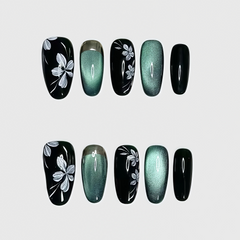 Oval-shaped green cat eye press-on nails with white floral line detailing and glossy finish.