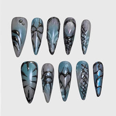 Stiletto-shaped press-on nails with bio-mechanical black detailing, chrome blue and gray gradient base, and futuristic 3D textures