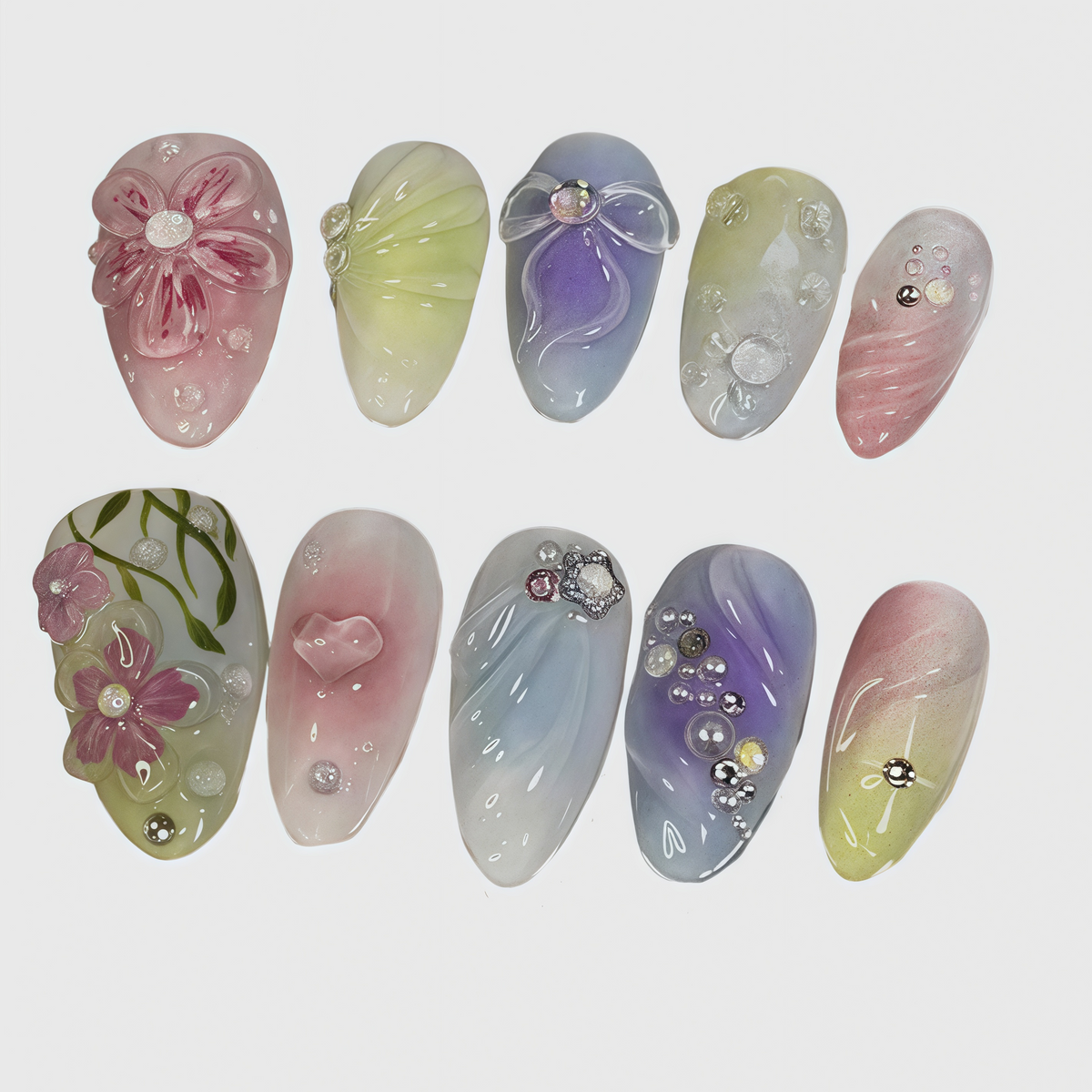 Set of oval-shaped pastel press-on nails featuring floral 3D decorations, gradient ombre colors, heart and bow motifs, and rhinestone embellishments

