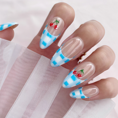 Almond-shaped press on nails with blue gingham French tips and cherry artwork