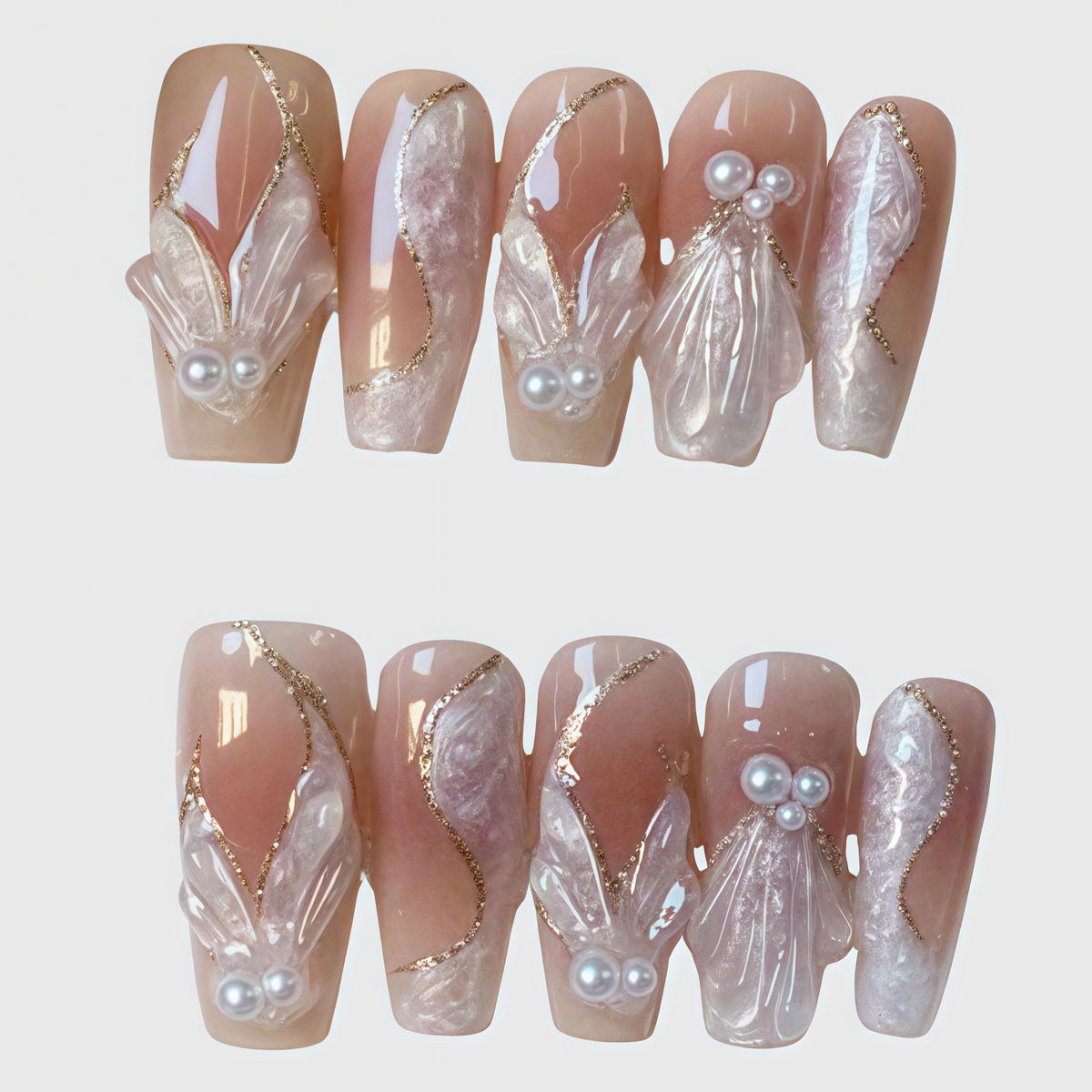 Coffin-shaped nude pink press-on nails with 3D shell and pearl designs, gold foil accents, and sculpted textures for a luxurious elegant look.

